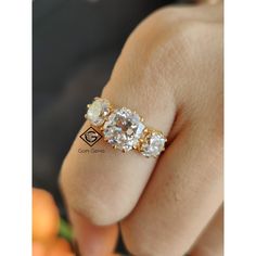 a woman's hand holding an engagement ring with three stones on the middle and one stone in the middle