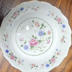 a white plate with pink, blue and yellow flowers on it sitting on a wooden table