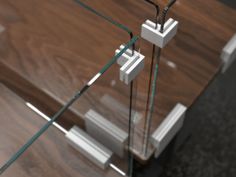 a glass and wood table with two white square objects on it's legs that are connected to each other