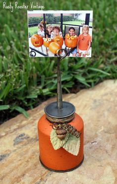 an orange vase with some pictures on it and a small tree in the middle of it