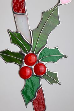 a stained glass christmas ornament with holly berries