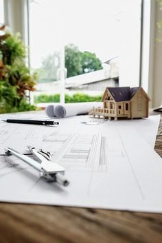 a house model on top of a table next to a pair of scissors and pencils