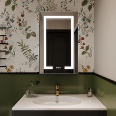 a bathroom sink with a lighted mirror above it and flowers on the wall behind it