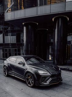 a black sports car parked in front of a tall building