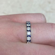 a woman's hand holding a ring with three diamonds on it and two blue sapphires in the middle