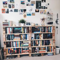 a bookshelf filled with lots of books in front of a wall full of pictures