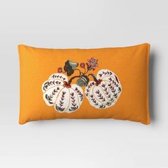 an orange pillow with two white pumpkins on the front and one red flower on the back