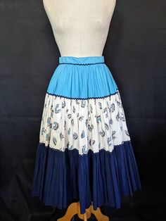 "This 50s cotton fiesta skirt is very full, over a circle actually, and has the most wonderful print of Indian Chief headdresses on the middle tier. The colors of turquoise, cream, navy, and red coral make a perfect match for Indian jewelry. Inside the waistband there are rows of rubber stitching to keep your blouse tucked in while dancing. The colors are bright and unfaded, there is a small side zipper, and the eyes for the hooks were moved to make the waistband tighter. Except for some slight Retro Blue Cotton Skirt, Chiefs Headdress, Indian Chief, 50s Fashion, A Circle, Red Coral, Indian Jewelry, Skirt Length, Tie Dye Skirt