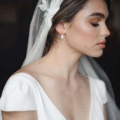 a woman wearing a white veil with flowers on her head and hair comb in her hand