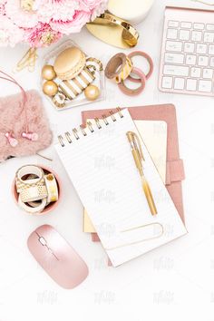 an office desk with pink flowers, notebook and computer mouse on it's side