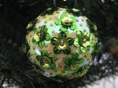 an ornament hanging from a christmas tree decorated with green and yellow flowers on it