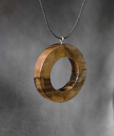 a wooden pendant hanging from a chain on a gray background with the word love written in it