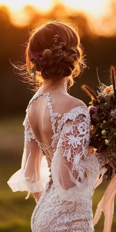 the back of a woman's dress with flowers in her hair, holding a bouquet