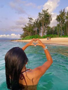 a woman in the water making a heart shape with her hands