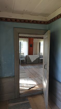 an open door leading to a living room with blue walls and wood floors in the background