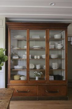 a large wooden cabinet with glass doors and shelves filled with dishes on top of it