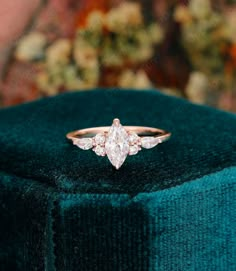 an engagement ring with three pear shaped diamonds on top of a green velvet covered box