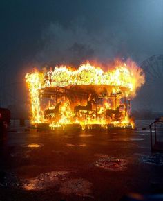 the fire is burning in front of an amusement park ride with horses on it's sides