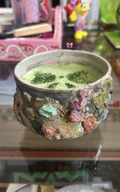 a bowl filled with green liquid sitting on top of a glass table next to other items