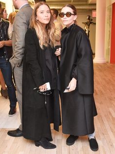 two women standing next to each other in black coats