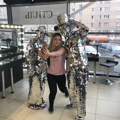 a woman standing next to two large metal bears