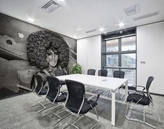 an office with black chairs and a white table in front of a large wall mural