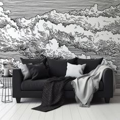 a black and white couch sitting in front of a wall with clouds painted on it