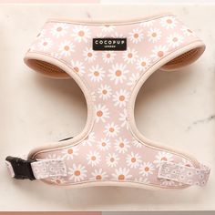 a pink and white floral print dog harness on a marble surface with the words cocopuu written across it