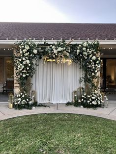 an outdoor wedding ceremony setup with white flowers and greenery on the side of the building