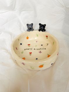 two small black dogs sitting in a bowl shaped like a dog bed with the words putty and spillie written on it