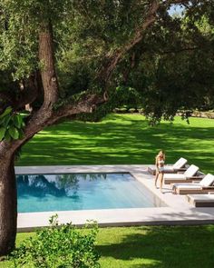 an empty swimming pool in the middle of a lawn with chaise lounges around it