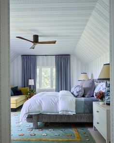 a bedroom with blue and white striped walls, carpeted flooring and ceiling fan