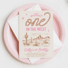 a pink and white plate with a card on it that says wild one in the west