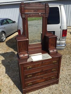 a wooden dresser with mirror and drawers in front of a van