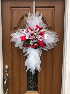 a red and white christmas wreath on the front door