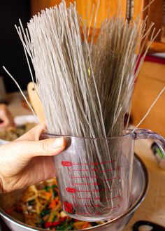 a person holding a glass mug filled with sticks