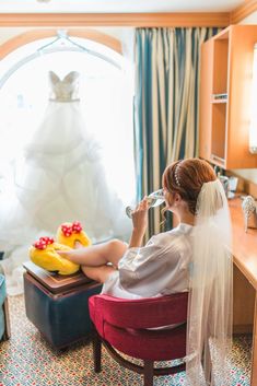 a woman sitting in a chair drinking from a bottle next to a dress on display