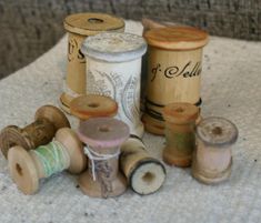 several spools of thread sitting on top of a white cloth next to some wooden spools