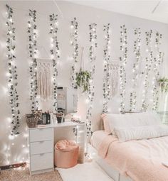 a bedroom decorated with white lights and greenery