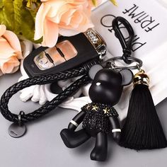 a key chain with a black cat on it and a flower in the background,