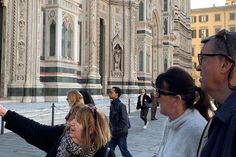 some people are standing in front of a building and one is holding a cell phone