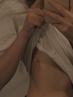 a woman with a cross tattoo on her stomach is taking a selfie in bed