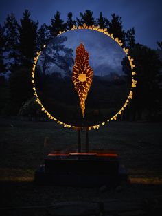 a lighted object in the middle of a field at night with trees in the background