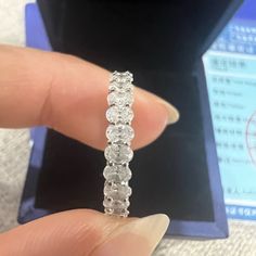 a person is holding a ring in their left hand and it has three rows of diamonds on each side