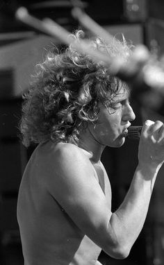 black and white photograph of a shirtless man brushing his teeth