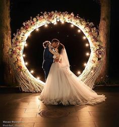 a bride and groom standing in front of a wedding arch with fairy lights on it