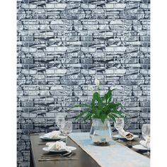 a dining table with place settings in front of a brick wall