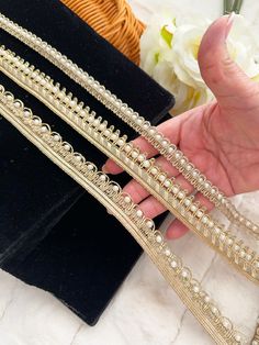 a hand is holding three different types of beaded trims on black velvet bags