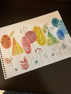 a drawing of flowers and leaves on a piece of paper with colored pencils next to it