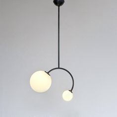 two white balls hanging from a black light fixture in a room with grey walls and flooring